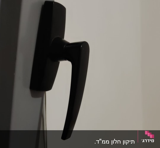 ידית תריס שחורה על מסגרת חלון